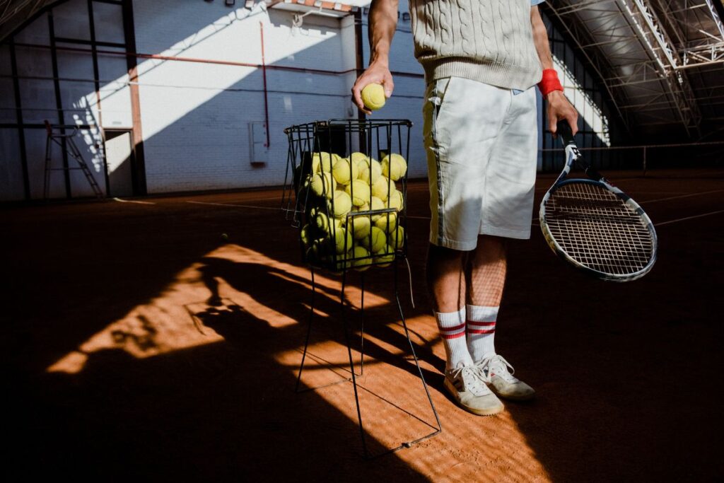Man holding a basket of tennis balls